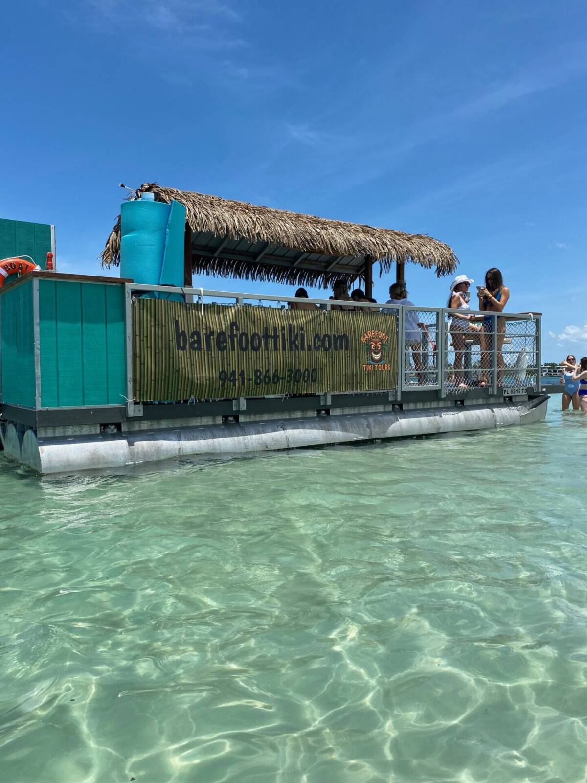 The Barefoot Tiki boat anchored in clear, shallow water